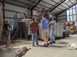 Distillery tour with the pot still and worm condenser. Two dogs laying on the floor.
