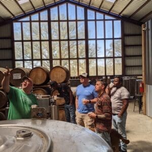 Cam pointing up at the still during a distillery tour. a large white oak is visible through a floor to ceiling window wall.
