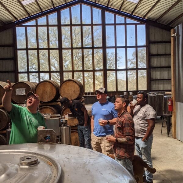 Cam pointing up at the still during a distillery tour. a large white oak is visible through a floor to ceiling window wall.