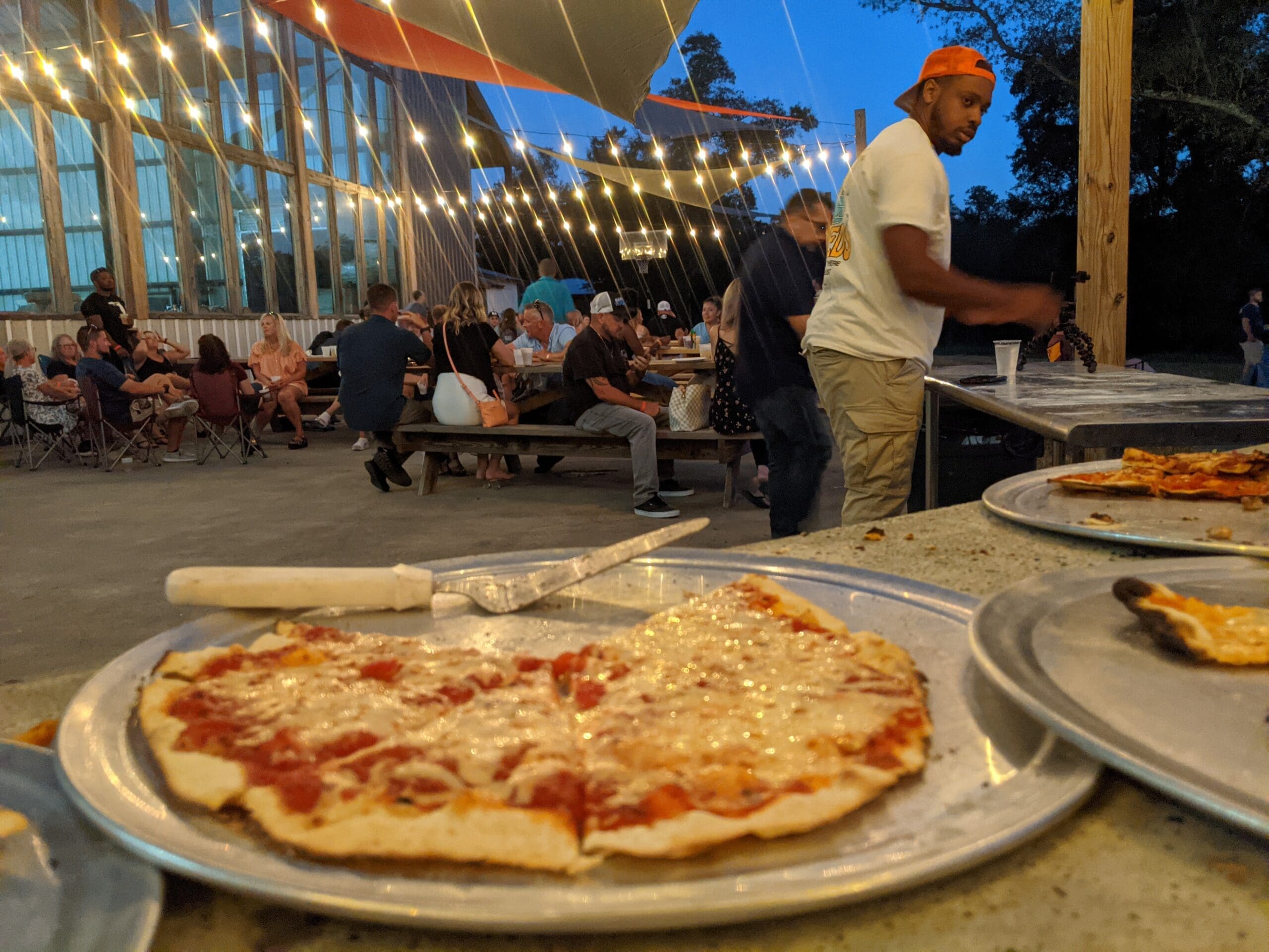 variety of pizzas with people having a good time in the background.