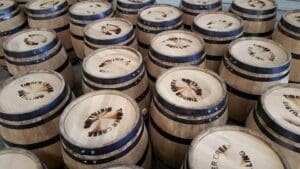 the frame is full of new american white oak barrels made in cuba missouri. they are standing on end with fresh brands reading timber creek distillery.